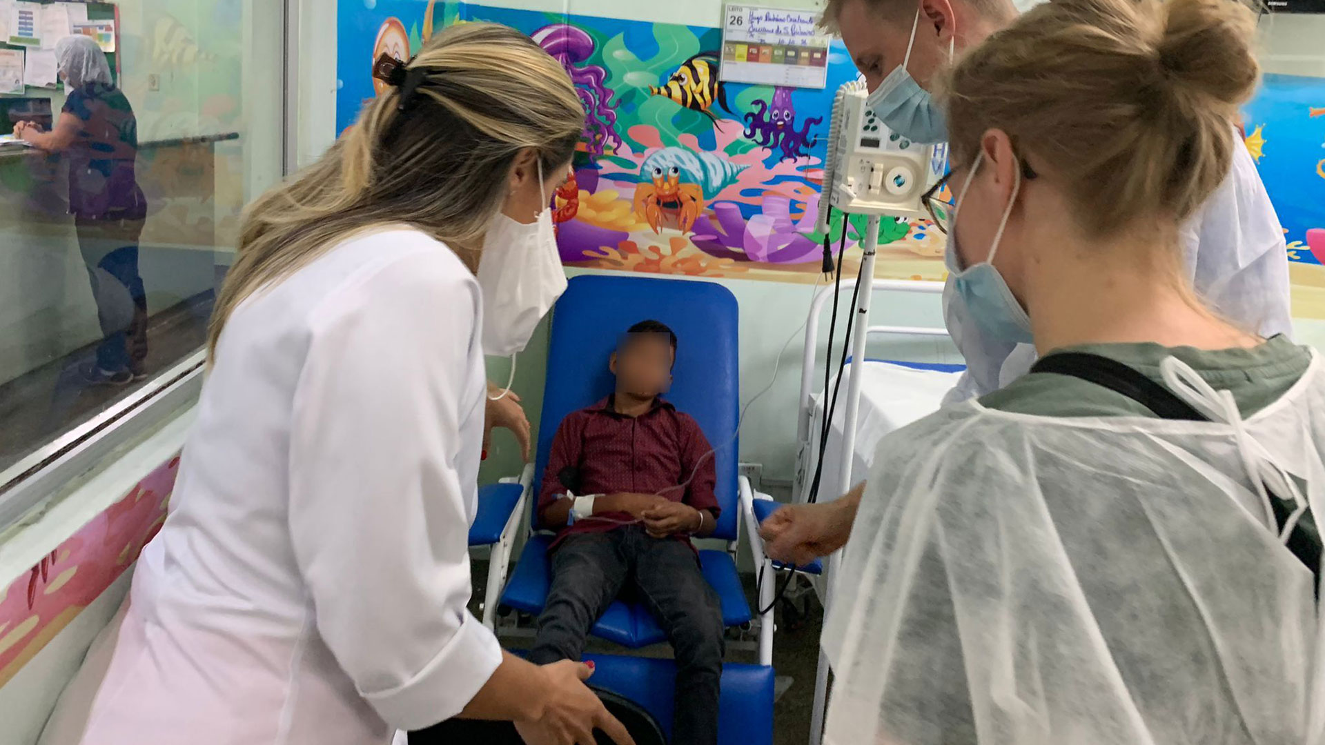 Ungt slangbidsoffer sidder i en hospitalsstol, mens han bliver tilset af sundhedspersonale. Foto: Magnus Hertz