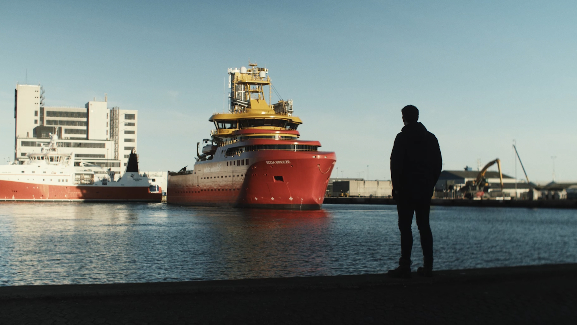 Silhuet af mand, der kigger ud mod en havn med et stort industrielt skib i baggrunden. ©MARTEC Silhuet af mand, der kigger ud mod en havn med et stort industrielt skib i baggrunden.