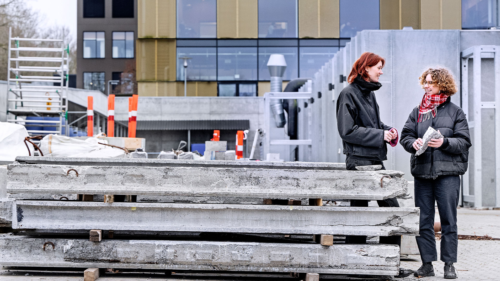 To kvinder står ved en bunke kasserede betonelementer udenfor en bygning. Foto: Bax Lindhardt