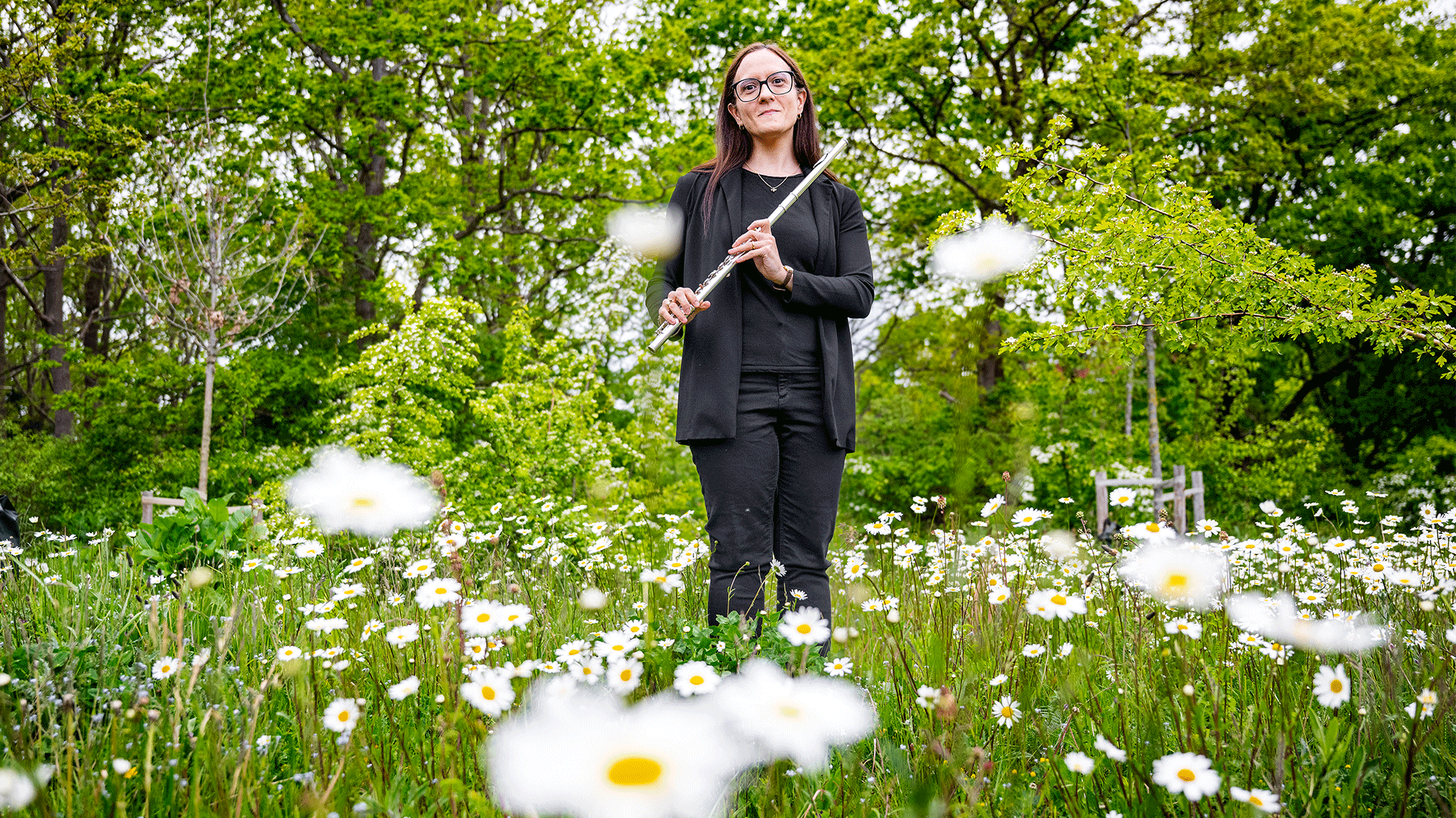 DTU-professor Maria Montanucci står på en eng med margueritter og holder en fløjte.
