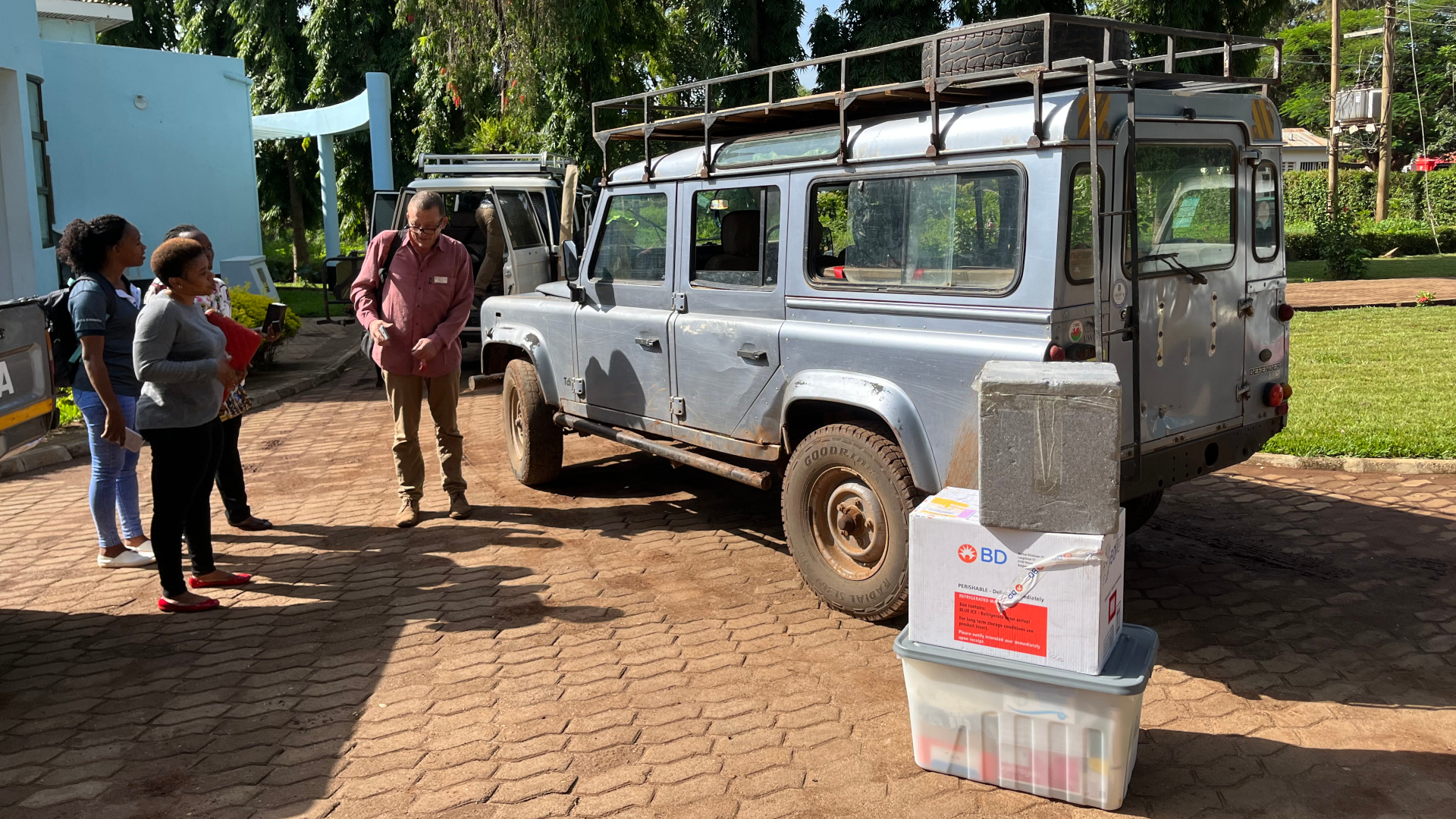 Happy Kumburu, Merian Shayo, Ruth Matiyas and Marco van Zwetselaar with equipment and Landrover.