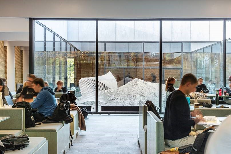 Students sitting in a common area in front of the artwork Indsande.