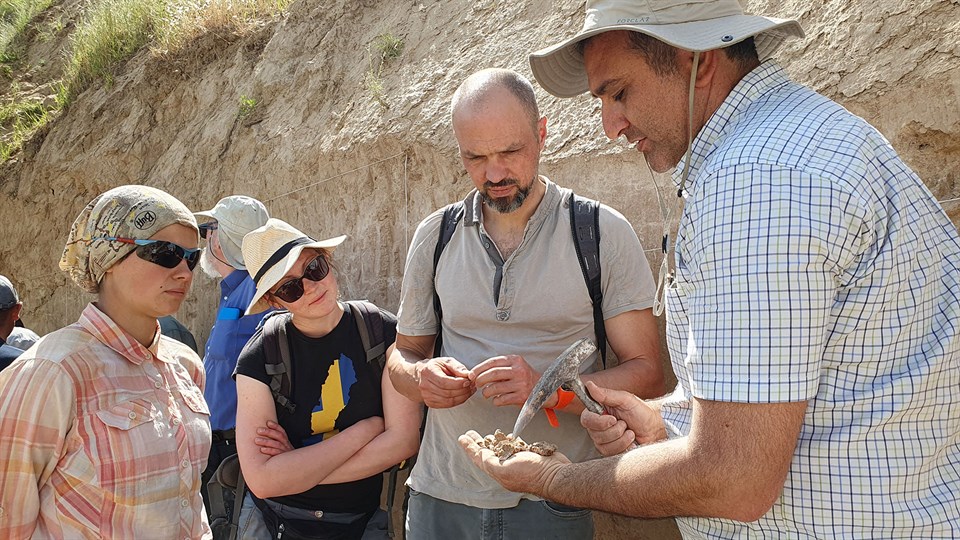 Two women and two men studying soil samples that one man is holding in his hand. Photo: Miriam Meister
