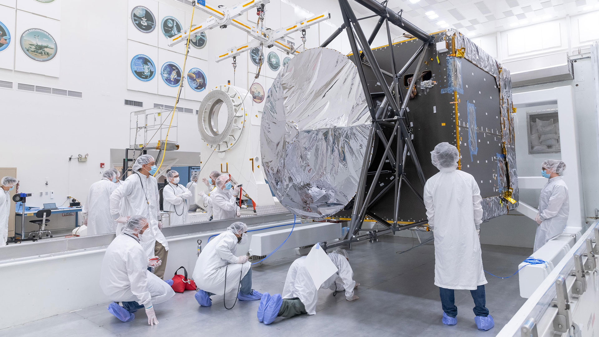 People in lab coats in NASA's Jet Propulsion Laboratory inspecting the Psyche Spacecraft. Photo: NASA/JPL-Caltech
