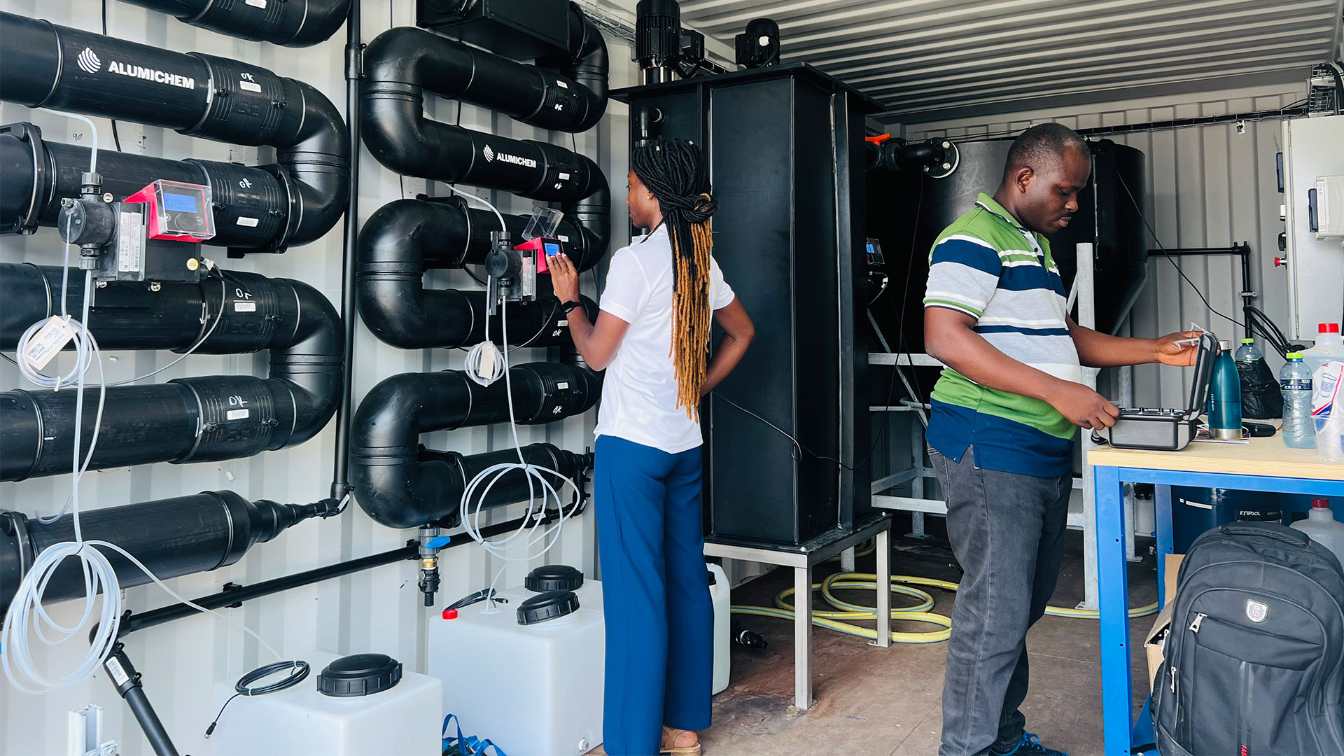 Two people operating equipment to purify water. Photo: Isaac Mensah-Boansi
