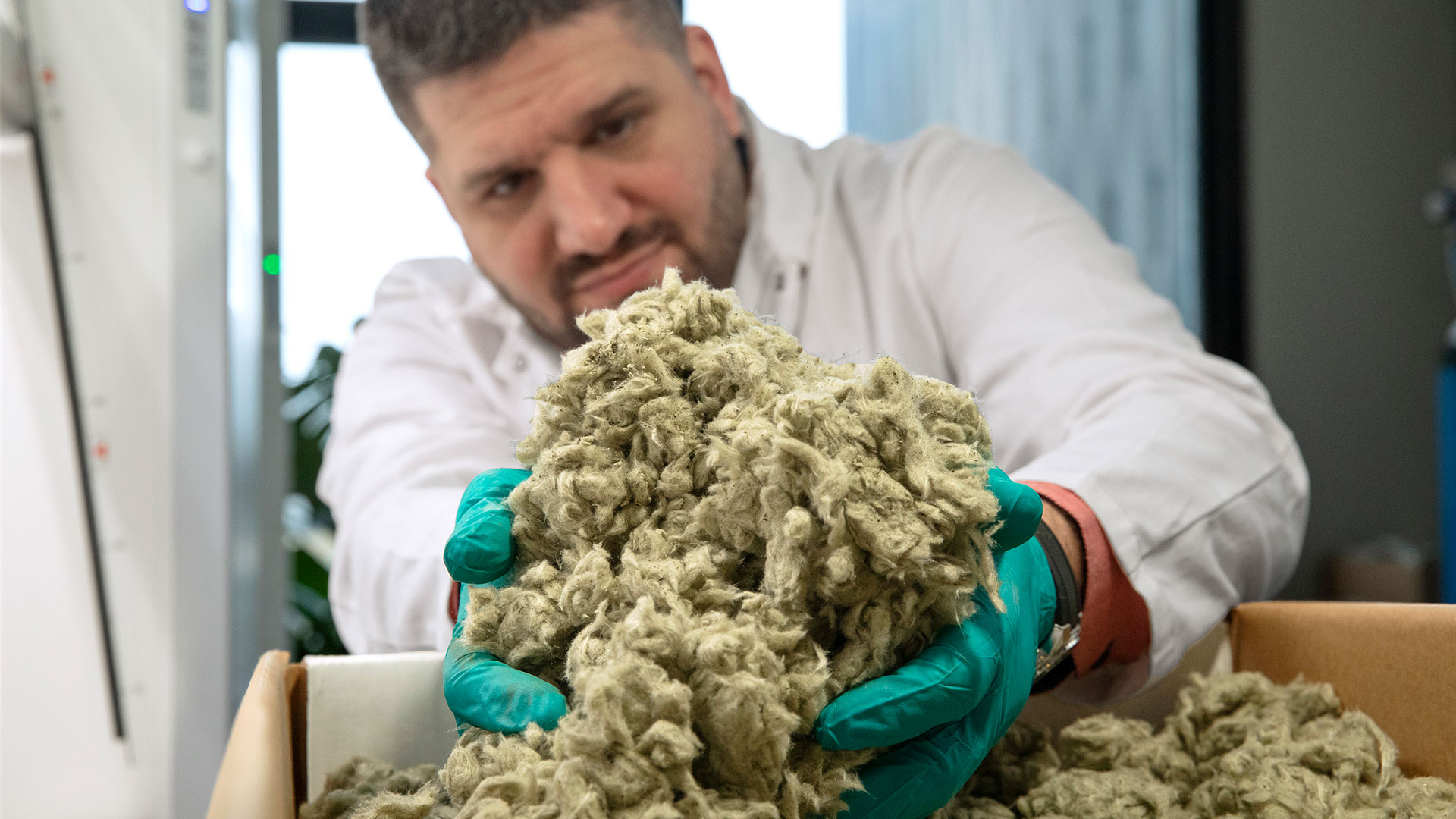 Man holding up handfuls of shredded stone wool. Photo: Sine Fiig