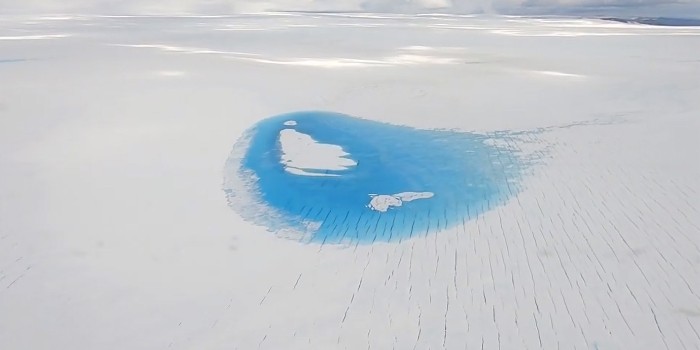 Under sommeren 2019 var afsmeltningen af indlandsisen i Grønland kraftigere end normalt. Billedet her er taget fra et fly i august inde over isen og viser en stor smeltevandssø og brede smeltevandsrender. (Foto: Andreas Stokholm/DTU Space)